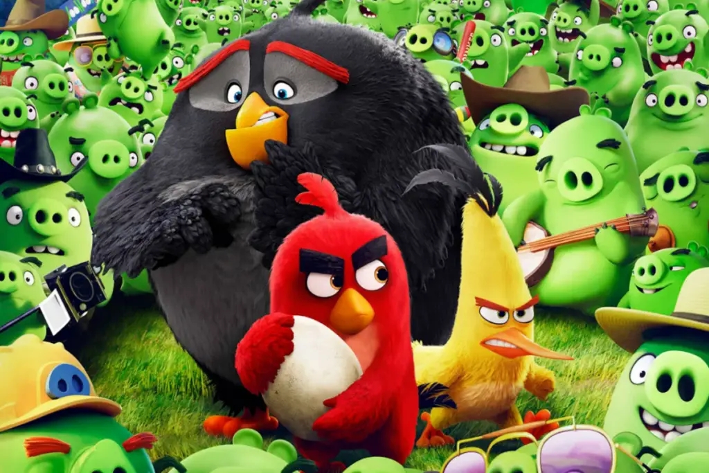 Imagem de três passarinhos, um preto, um amarelo e um vermelho segurando um ovo, cercados por porcos verdes