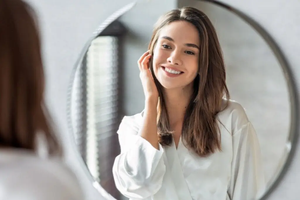 Mulher sorrindo e olhando o rosto em um espelho 