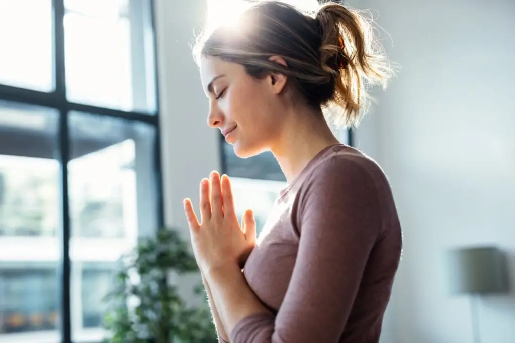 Jovem orando na sala de casa