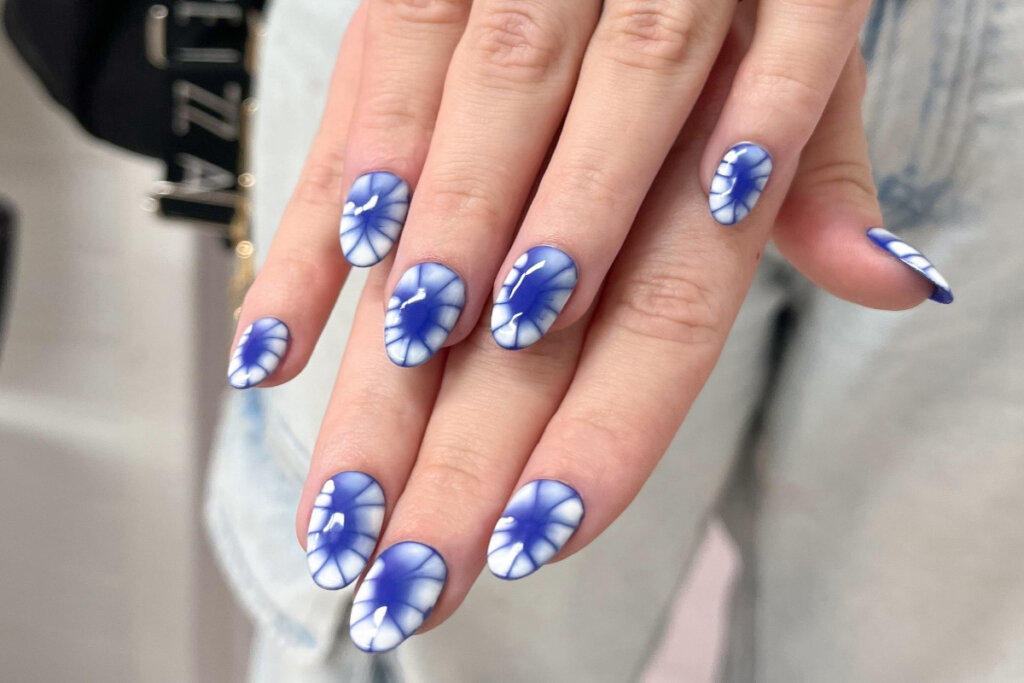 duas mãos com unhas em tons de azul e branco