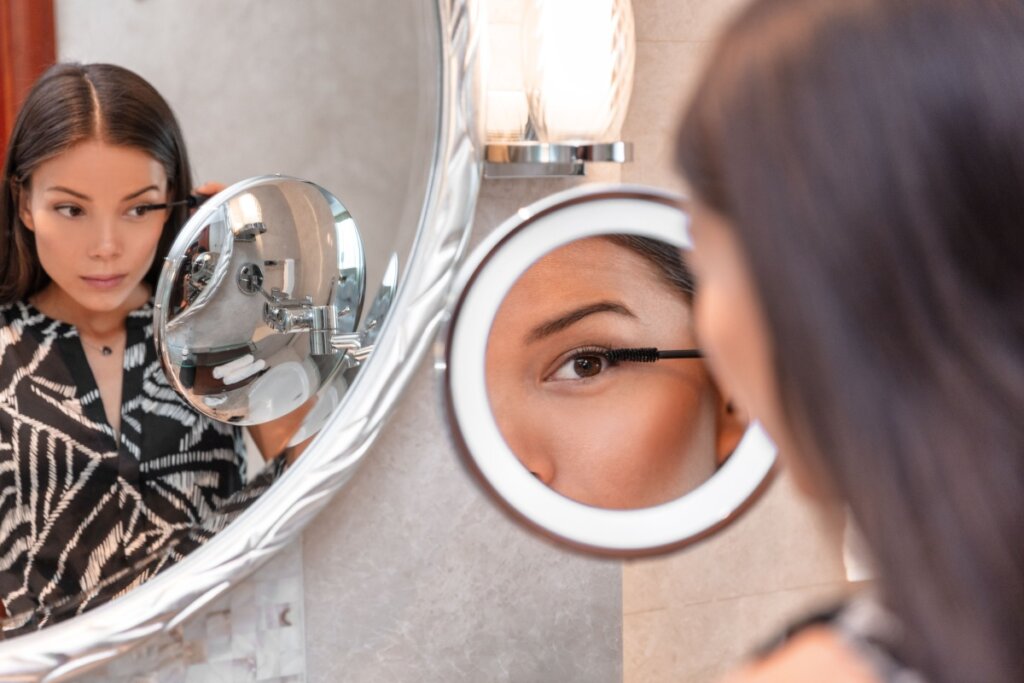 Mulher usando um espelho redondo com led para se maquiar