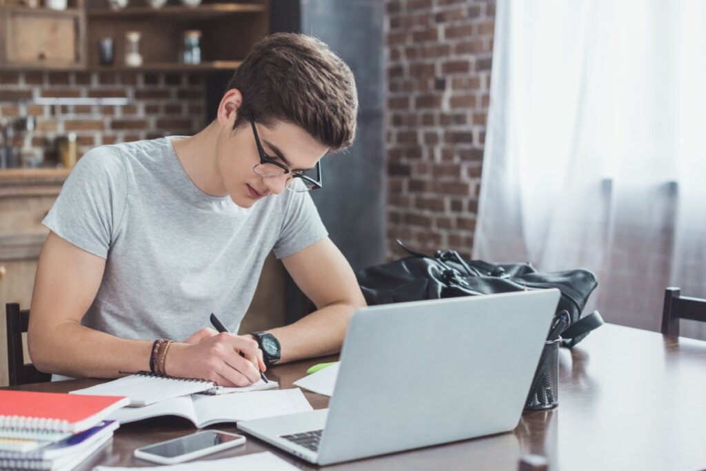 Jovem concentrado estudando em frente a um notebook e sentado