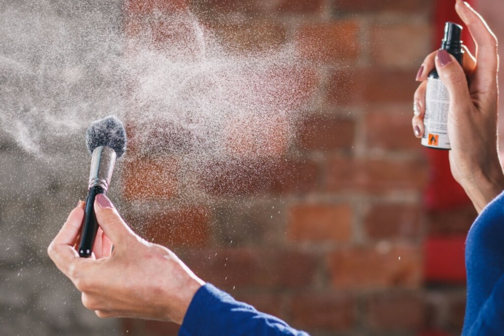 Mãos jogando um produto em um pincel com spray 