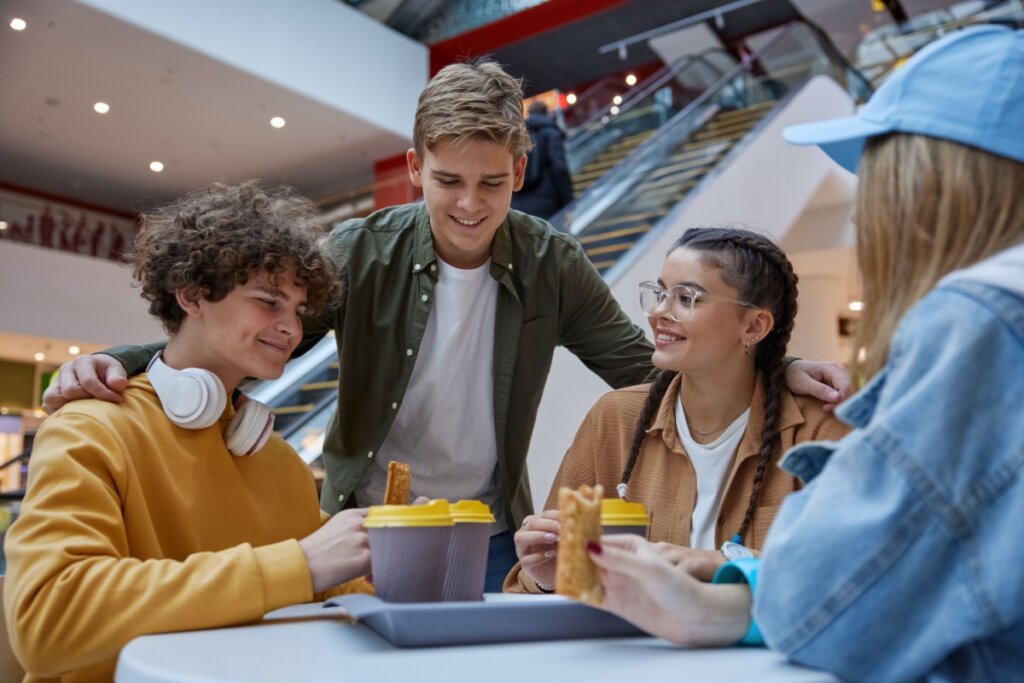 Jovens reunidos em uma mesa em uma praça de alimentação