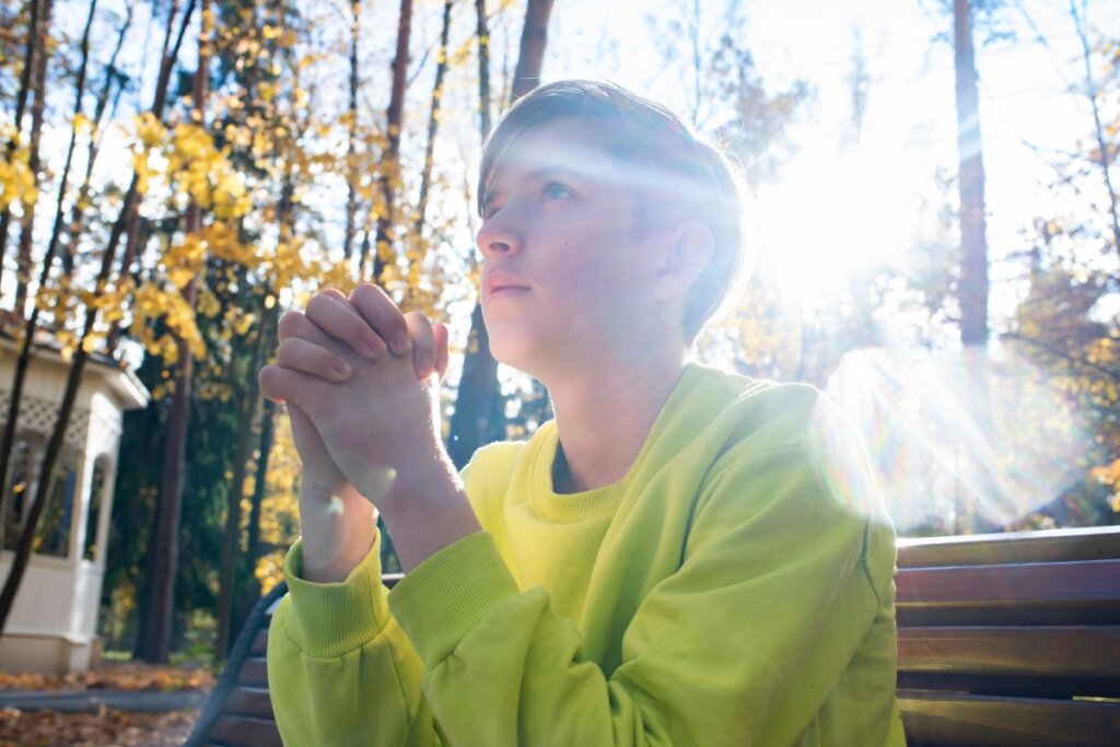 Menino sentando em um parque orando e olhando para o céu