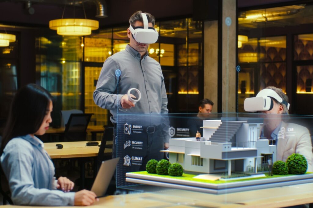 Três pessoas em uma sala, duas delas usando óculos de realidade 3D, olhando para um projeto arquitetônico