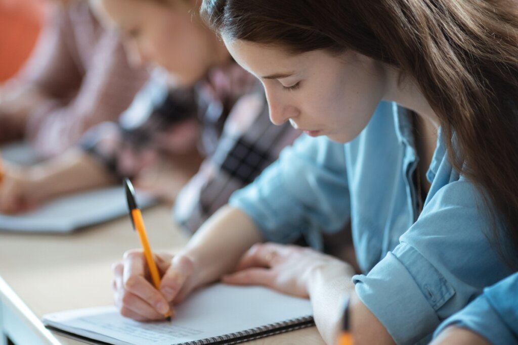 Jovem estudante fazendo prova usando caneta preta