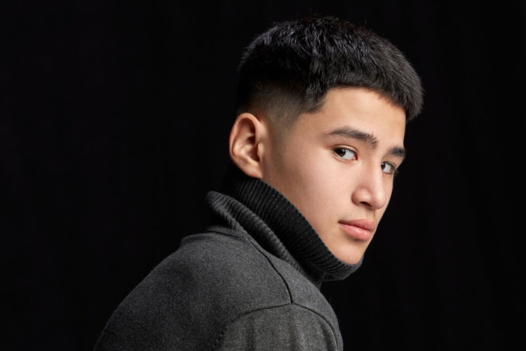 menino jovem de blusa preta de gola alta olhando de lado