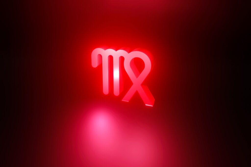 Ilustração em vermelho do símbolo do signo de Virgem em fundo vermelho