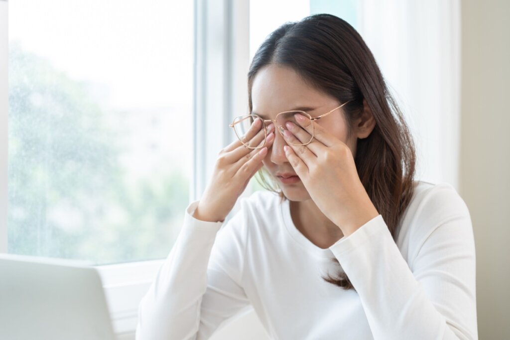 Mulher com a cabeça baixa e as duas mãos nos olhos 