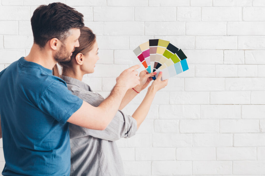 Homem e mulher segurando diversas paletas de cores para pintar a parede
