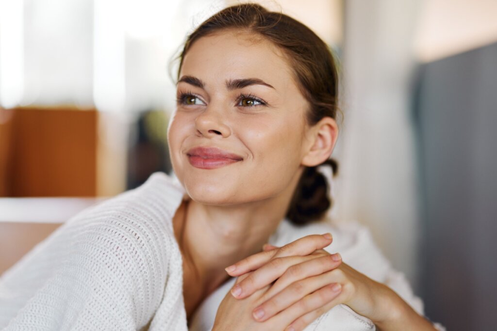 Mulher maquiada, sorrindo e olhando para o lado