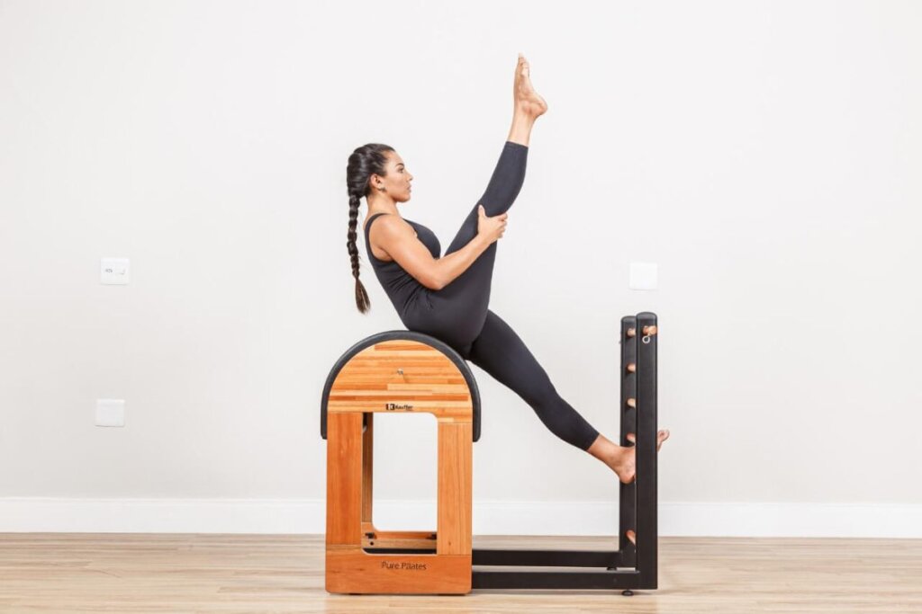 Mulher em cima de um barrel de pilates fazendo Single Straight Stretch