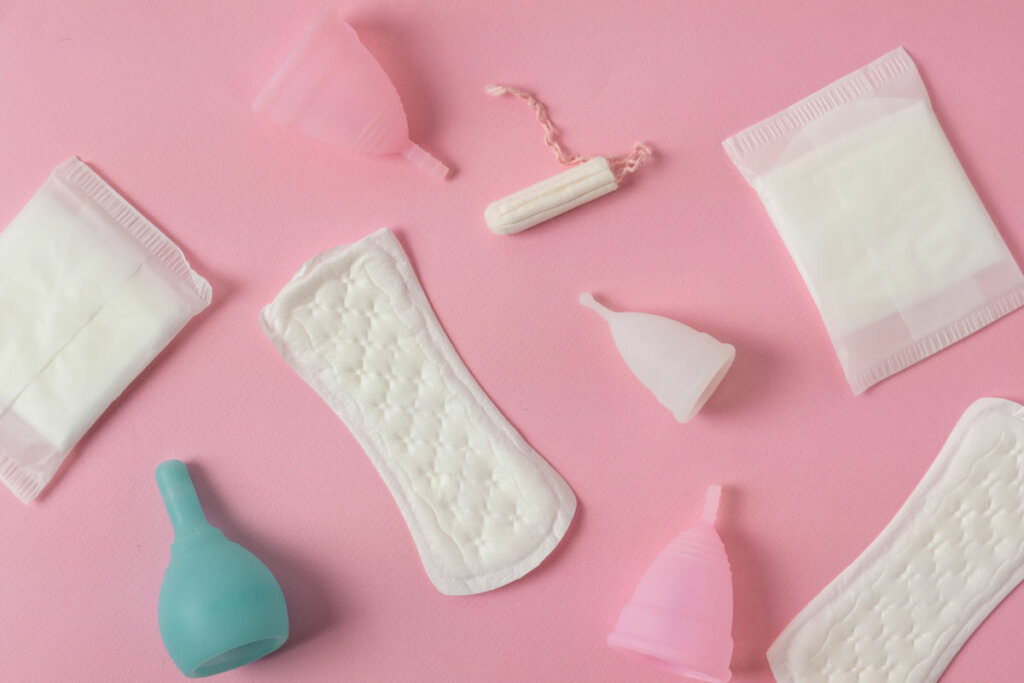 Absorventes e coletores menstruais em fundo rosa
