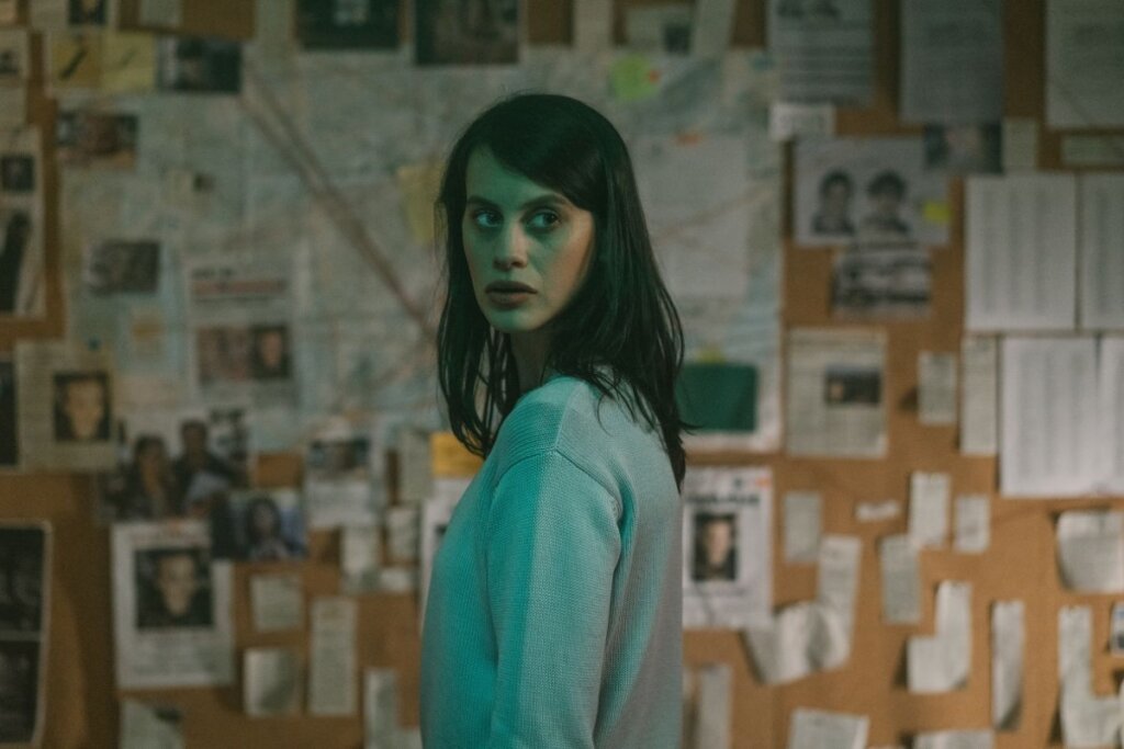 Mulher em ambiente com mural com recortes e fotos de pessoas