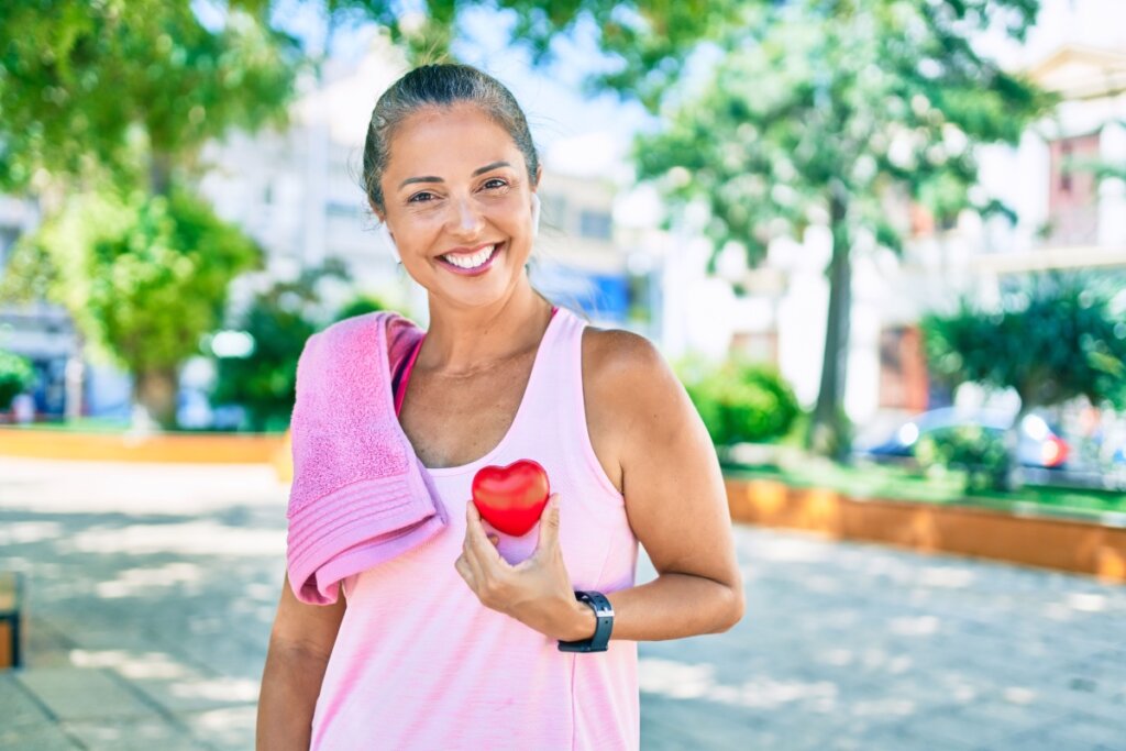 Mulher após caminhada segurando coração em miniatura e sorrindo