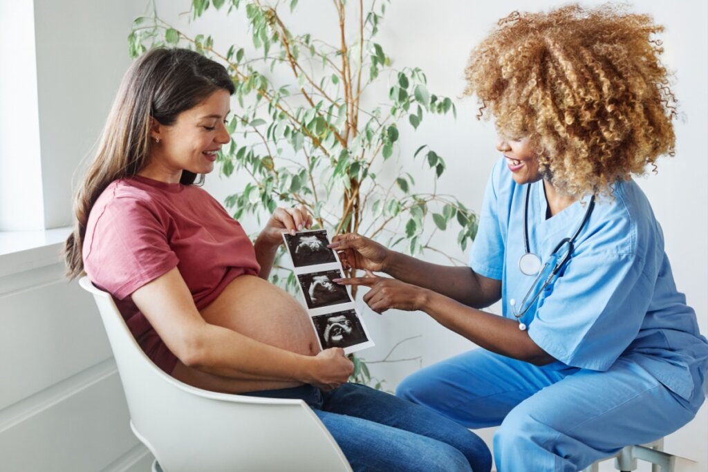 Mulher grávida sentada e uma médica a sua frente mostrando um ultrassom morfológico