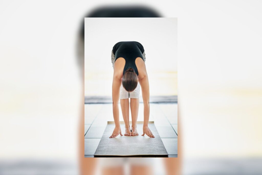 Mulher fazendo rolamento da coluna em cima de um tapete de ioga preto 