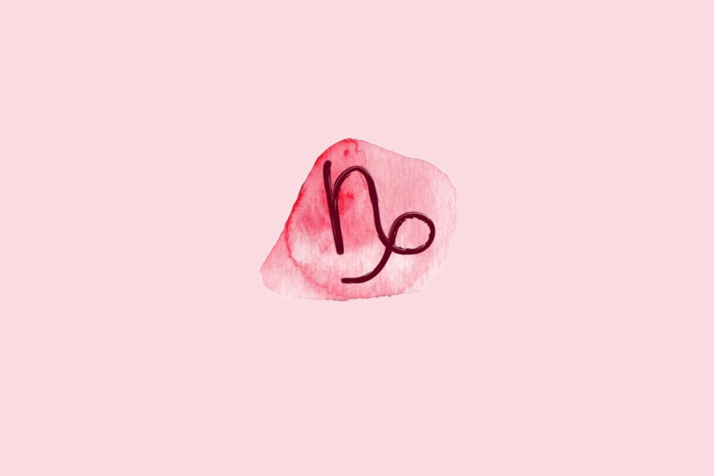 Ilustração do signo de Capricórnio contendo o símbolo de uma linha curva semelhante à letra N com um laço circular na base em aquarela rosa sobre fundo rosa-claro