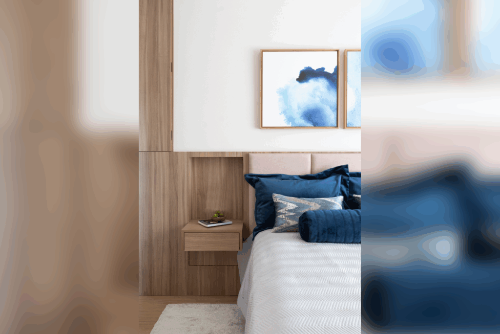 Quarto com cama, cabeceira em painel de madeira, mesa de cabeceira suspensa e quadros sobre a parede