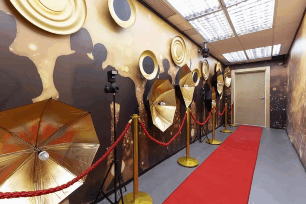 Corredor da casa do BBB 26 com tapete vermelho, câmeras e painéis decorativos nas paredes