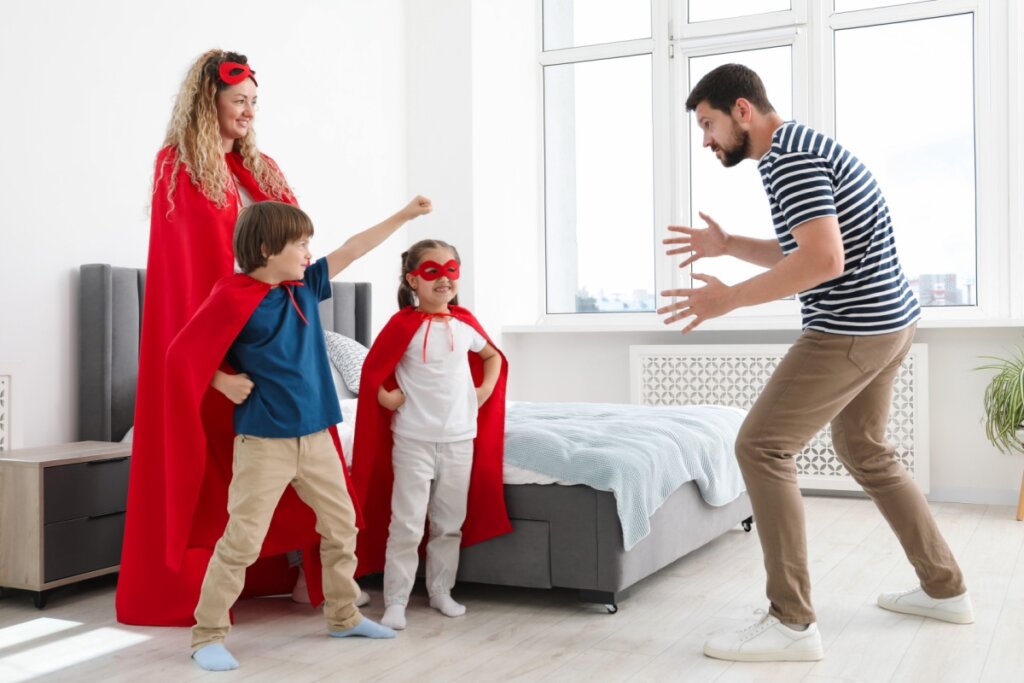Duas crianças e dois adultos fantasiados brincando em sala de estar 