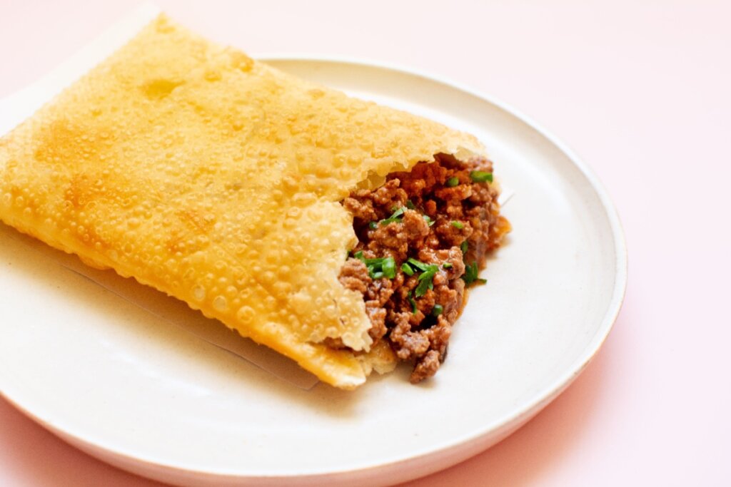 Pedaço de pastel de carne moída com cheiro-verde em prato branco