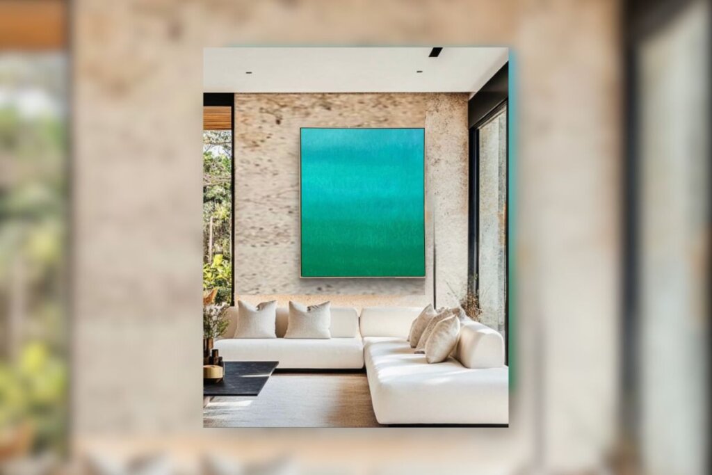 Sala de estar com uma tela com arte azul e verde, pendurada em uma parede cor de areia. Sofá off-white com almofadas bege à frente