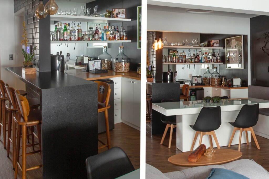 Bar residencial com balcão em granito, prateleiras com garrafas e cadeiras posicionadas ao redor da bancada