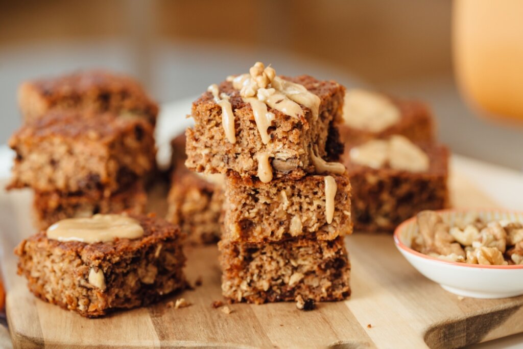 Três pedaços de bolo de banana com nozes e manteiga de amendoim empilhados em uma mesa de madeira 