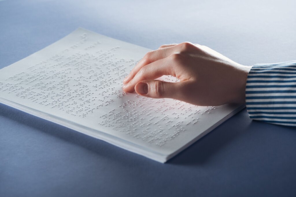 Mão em cima de um livro escrito em braille