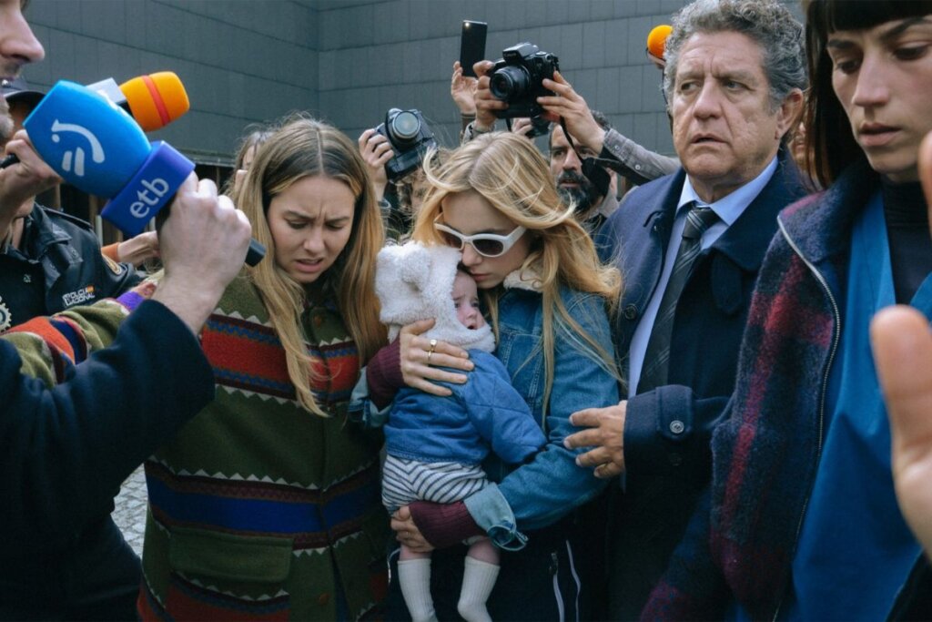 Cena da série "Naquela Noite", com repórteres cercando uma personagem enquanto ela segura um bebê