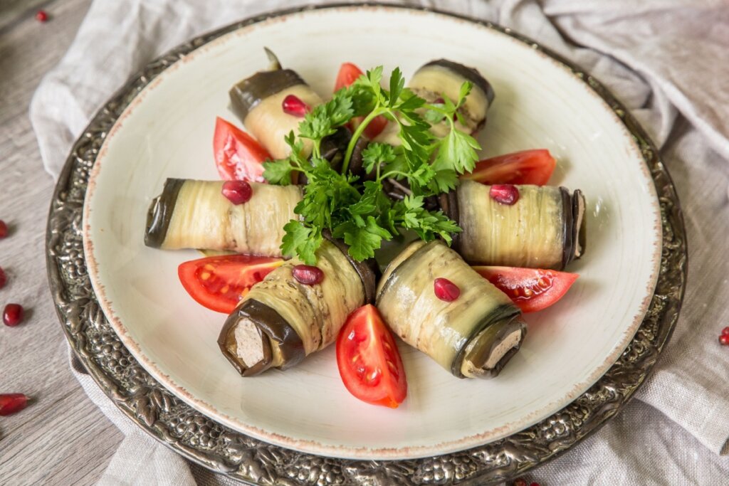 Prato branco com rolinhos de berinjela e tomates 