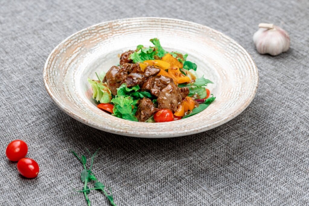 Prato branco com salada com fígado e abóbora 