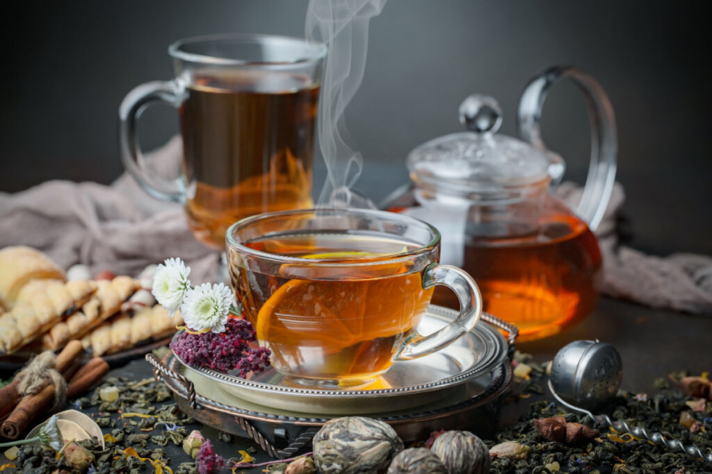 Três recipientes com chá quente em cima de uma mesa decorada com pequenas flores