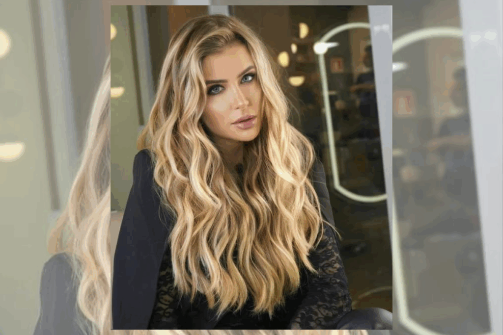 Mulher com o cabelo longo, ondulado, em tons de loiro usando blazer preto