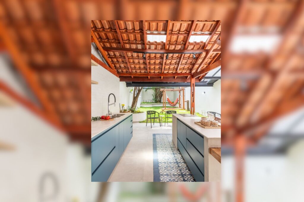 Área gourmet com telha de barro e telha translúcida, com bancadas azuis e paredes brancas