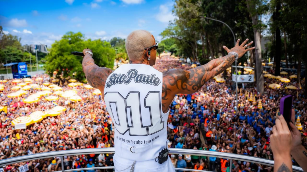 Léo Santana com os braços abertos em frente a uma multidão de foliões