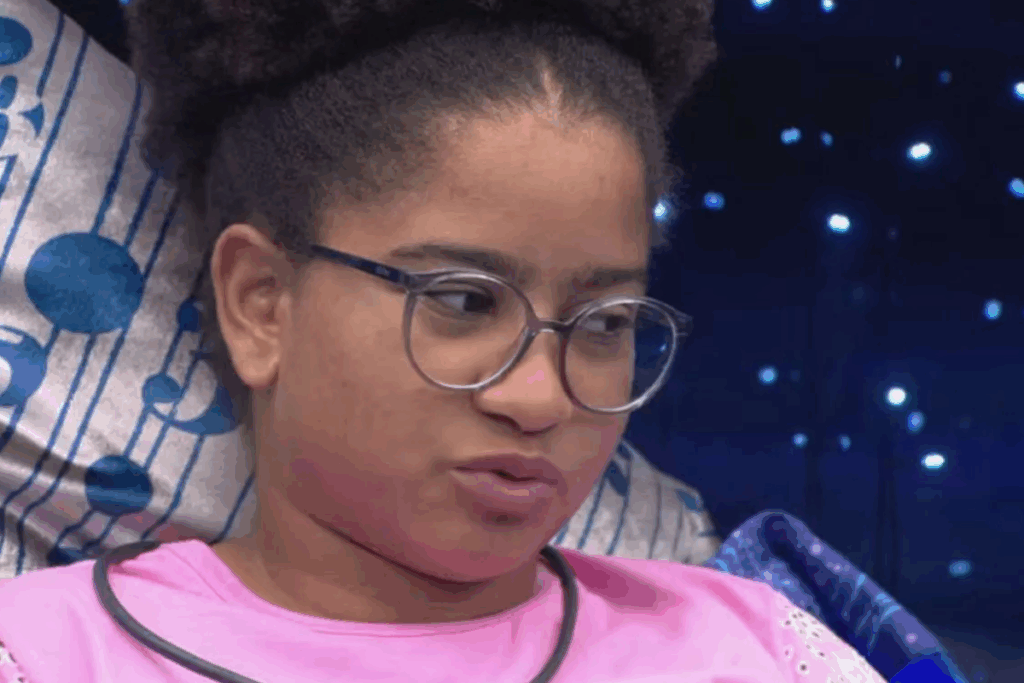 Milena, do BBB 26, usando óculos e roupa branca em fundo azul