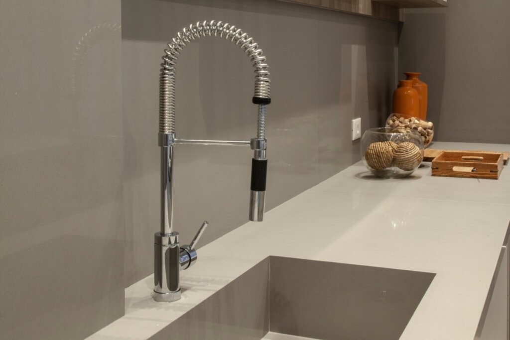 Torneira de metal longa em uma cozinha com bancada branca