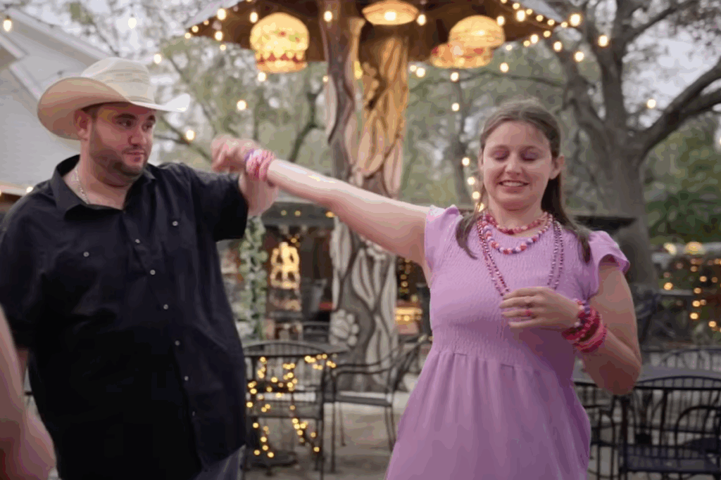 Homem e mulher dançando ao ar livre sob luzes decorativas em ambiente aconchegante