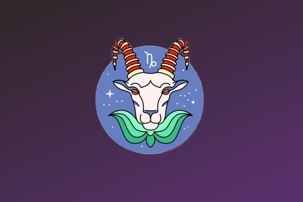 Ilustração do signo de Capricórnio. Mostra a cabeça de uma cabra branca de frente, com olhos puxados e pequenos detalhes azuis. Ela possui chifres longos e curvados, decorados com listras horizontais vermelhas e amarelas. Abaixo do queixo, há uma gola ou elemento decorativo que lembra folhas verdes. O símbolo de Capricórnio está em branco acima da cabeça do animal.