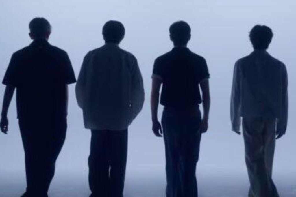 Cena do filme "ENHYPEN [Walk The Line Summer Edition] In Cinemas", com os integrantes do grupo em frente a um fundo branco e virados de costas 