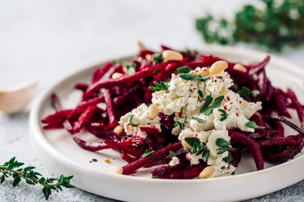 Salada de espaguete de beterraba com ricota e nozes em um prato branco 