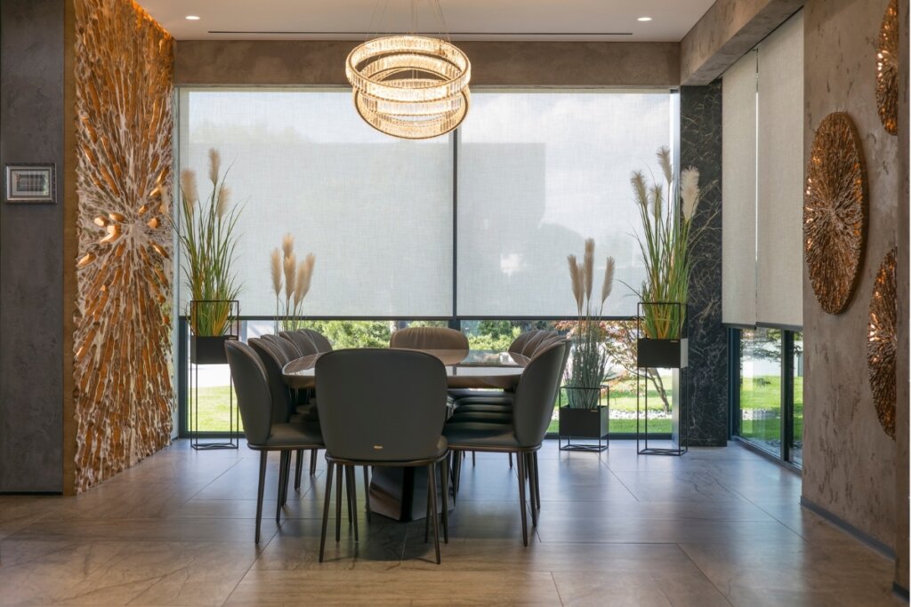 Apartamento com janela do piso ao teto com plantas em frente e mesa com quatro cadeiras 