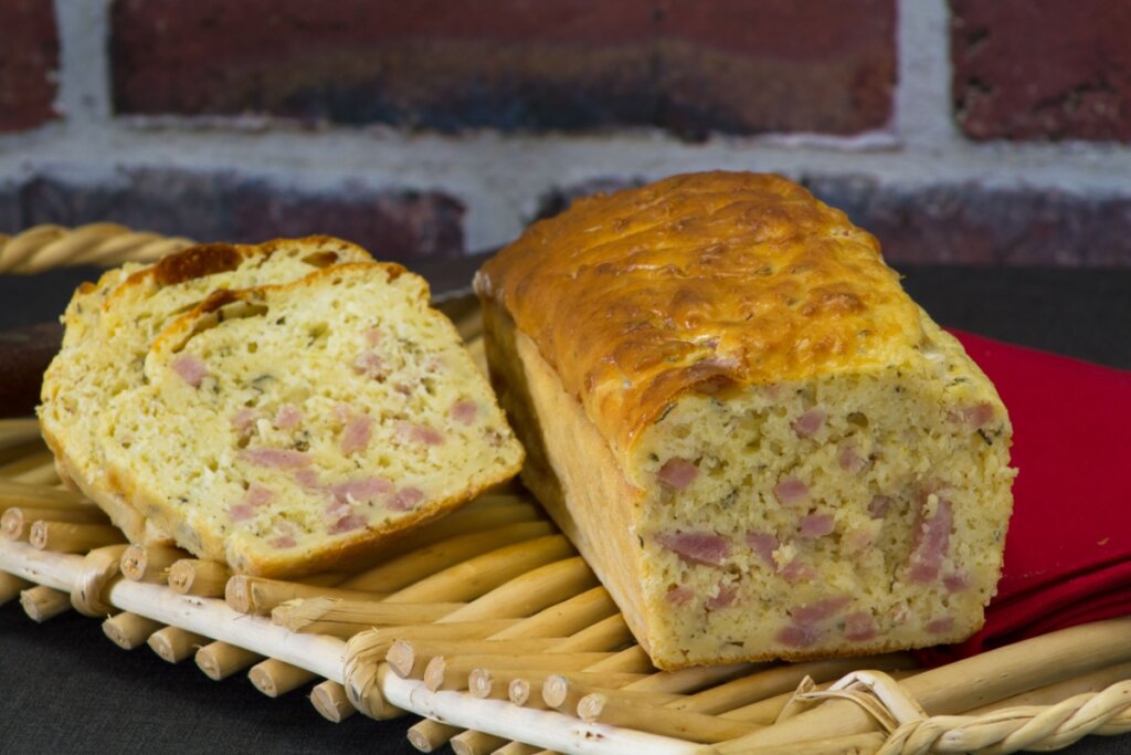 Pão salgado de liquidificador cortado, com interior macio recheado com pedaços de presunto e superfície levemente dourada