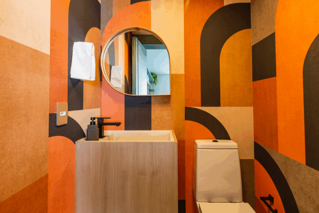Lavabo com paredes em padrões geométricos em tons de laranja e marrom criando um ambiente marcante