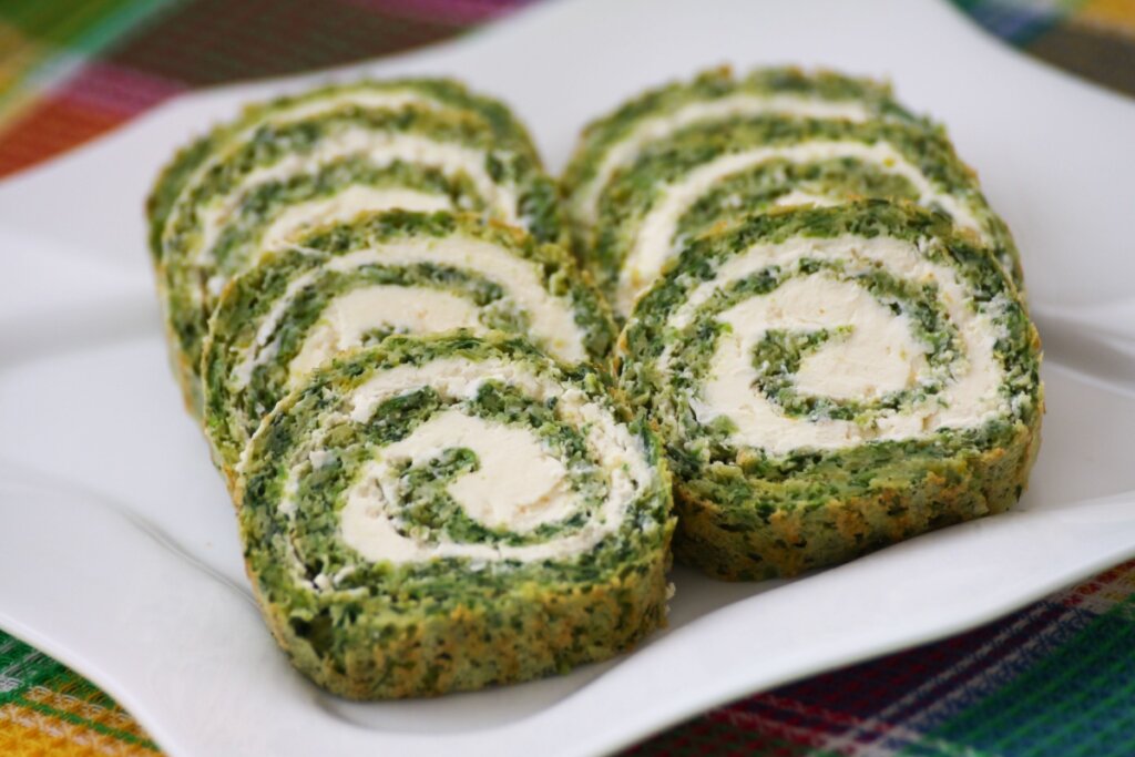 Rocambole de espinafre com ricota fatiado em um prato branco