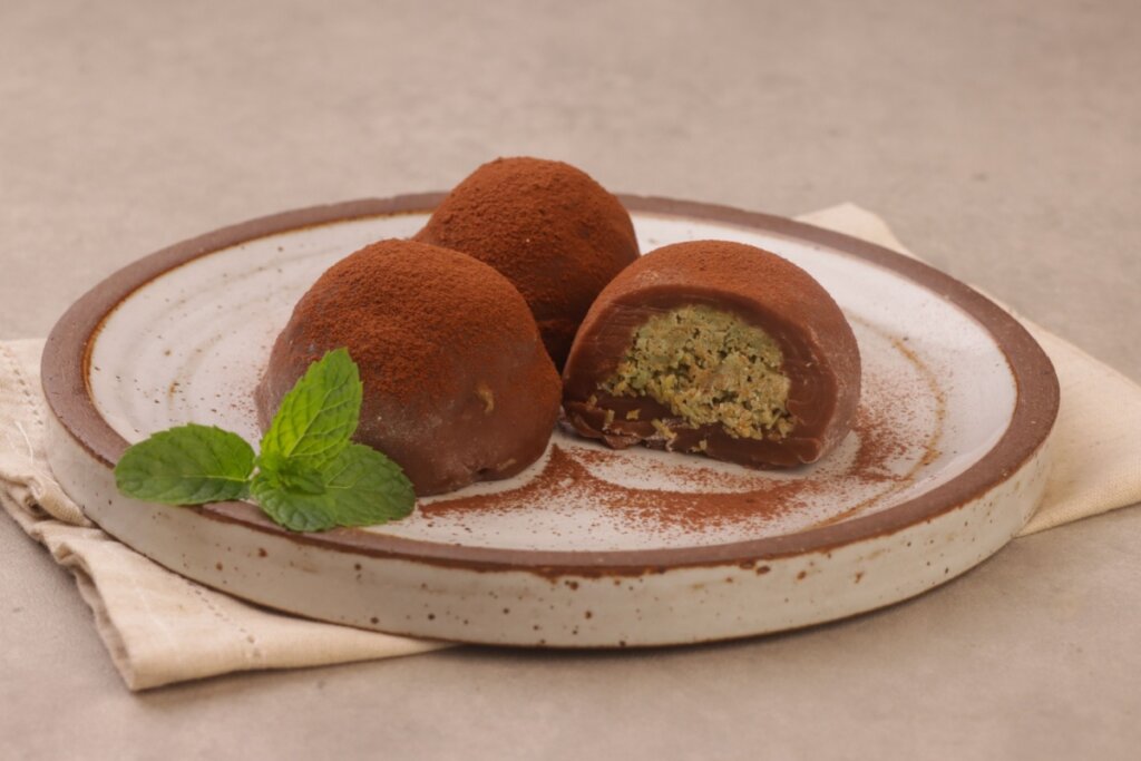 Bombom de pistache servido em prato de cerâmica em cima de bancada de pedra