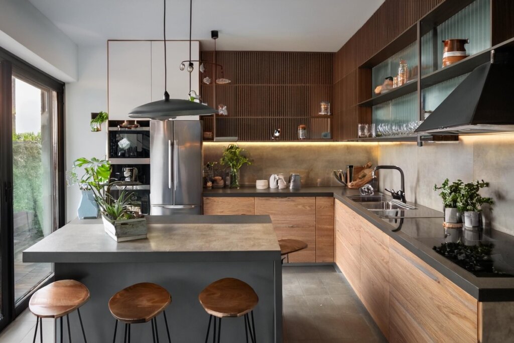 cozinha com armários em madeira, e bancada de pedra com banquetas de madeira, com detalhes em branco e prateleiras com itens de decoração